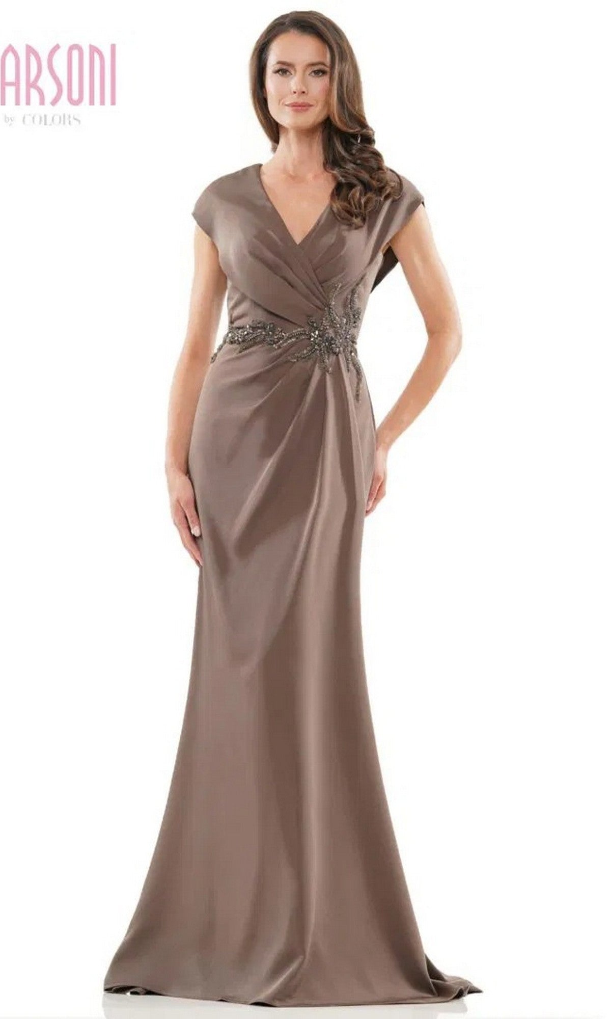 A woman stands wearing the Marsoni MV1226 long formal dress in dark taupe, featuring a floor-length sheath silhouette, short sleeves, a V-neckline, and decorative waist embellishments.